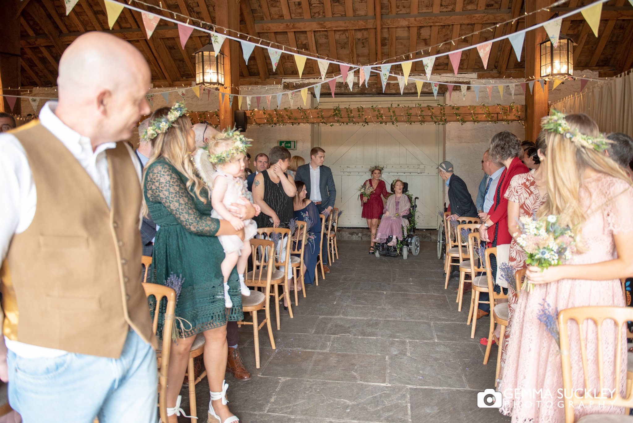 a bridesmaid in her wheel chair comes down the aisle at east riddlesden wedding