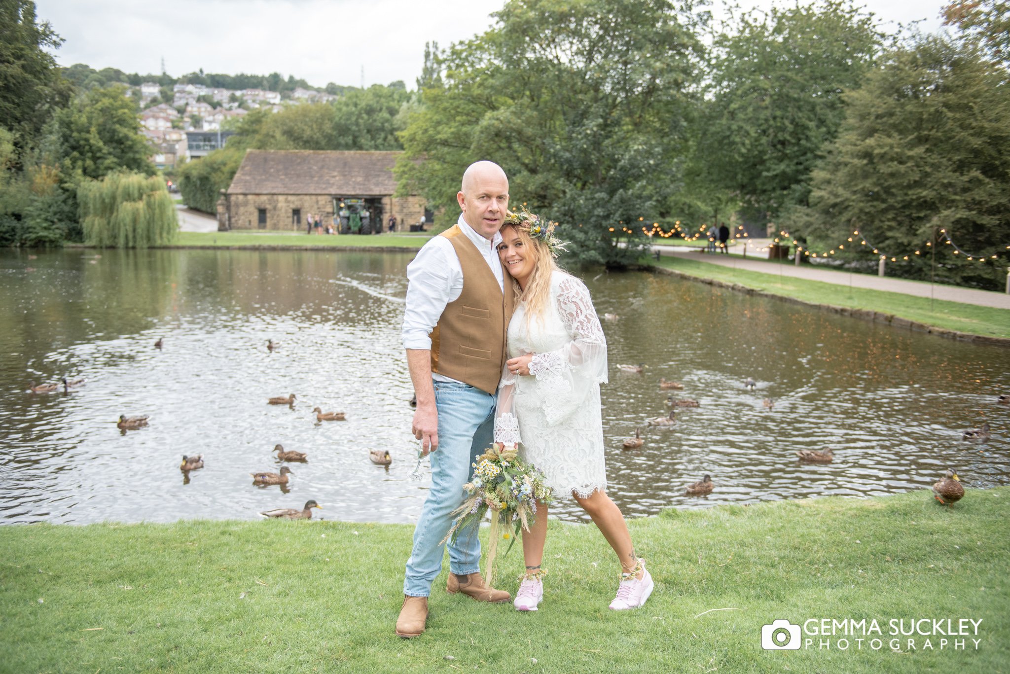 bride and groom smiling for the camera by the pond at east riddlesden hall