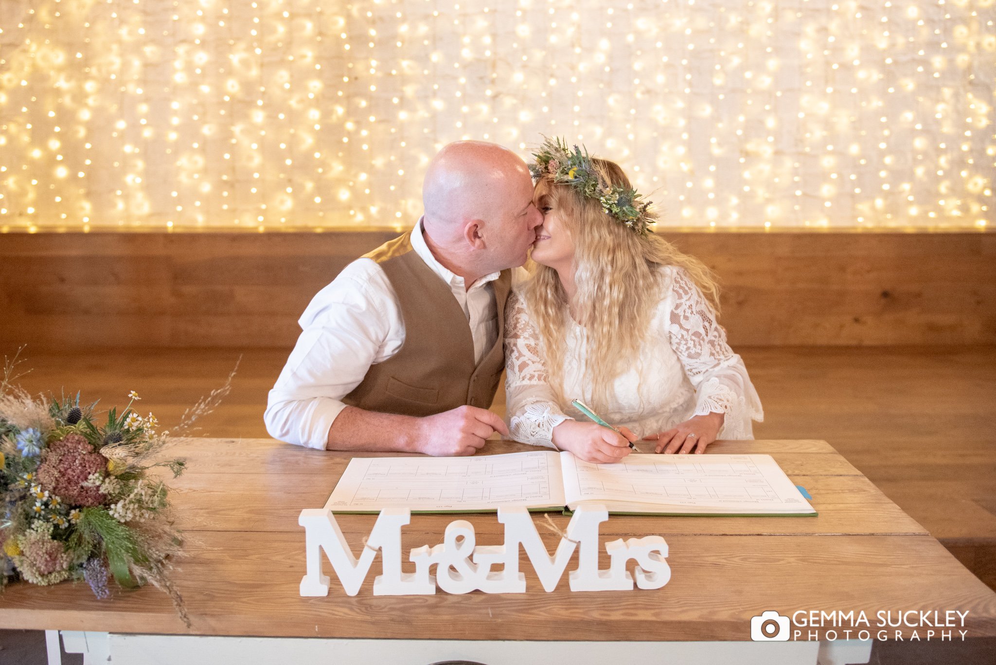 bride and groom kiss as they sign the register 
