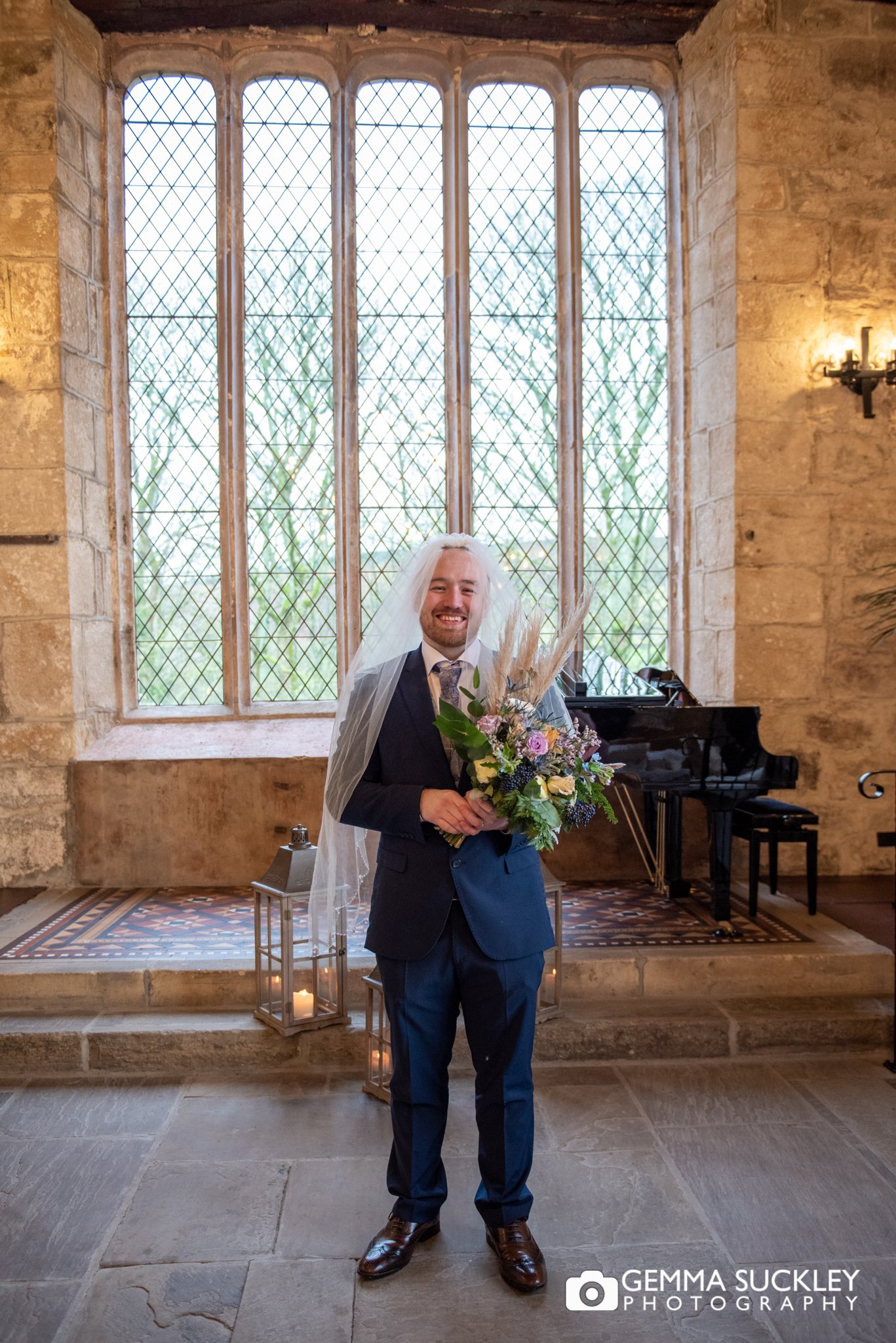 the groom wearing his wife's veil and holding the bouquet 