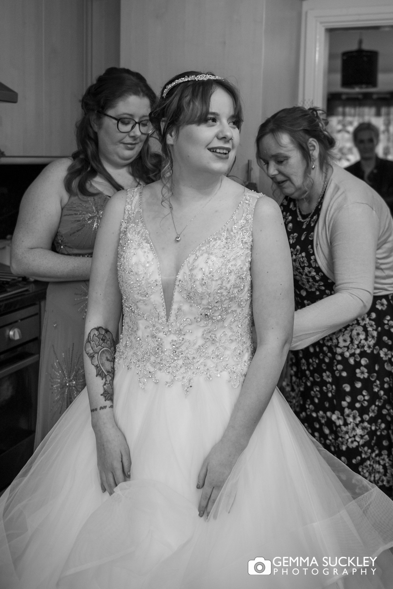 black and white photo of the bride being helped into her wedding dress