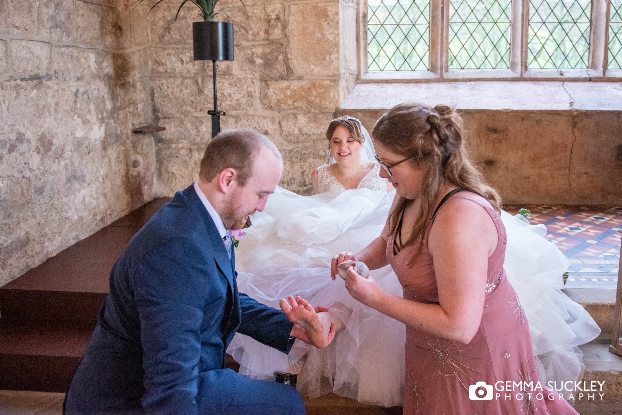 the groom and bridesmaid changing the brides shoes in the priest house