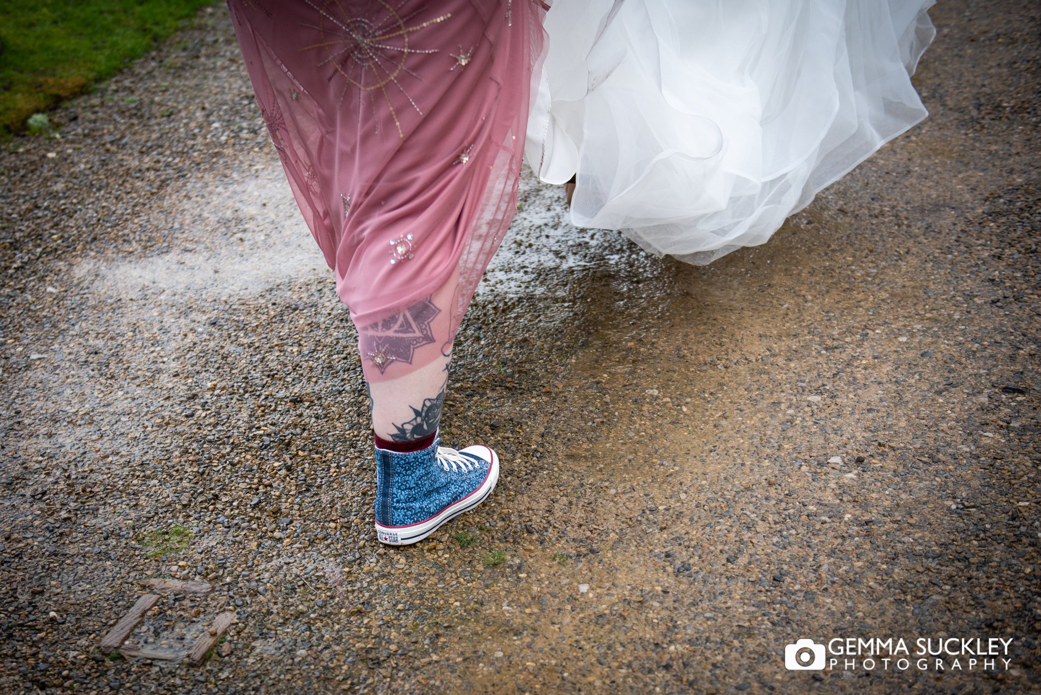 photo of the bridesmaid feet wearing converse as her holds up the brides dress