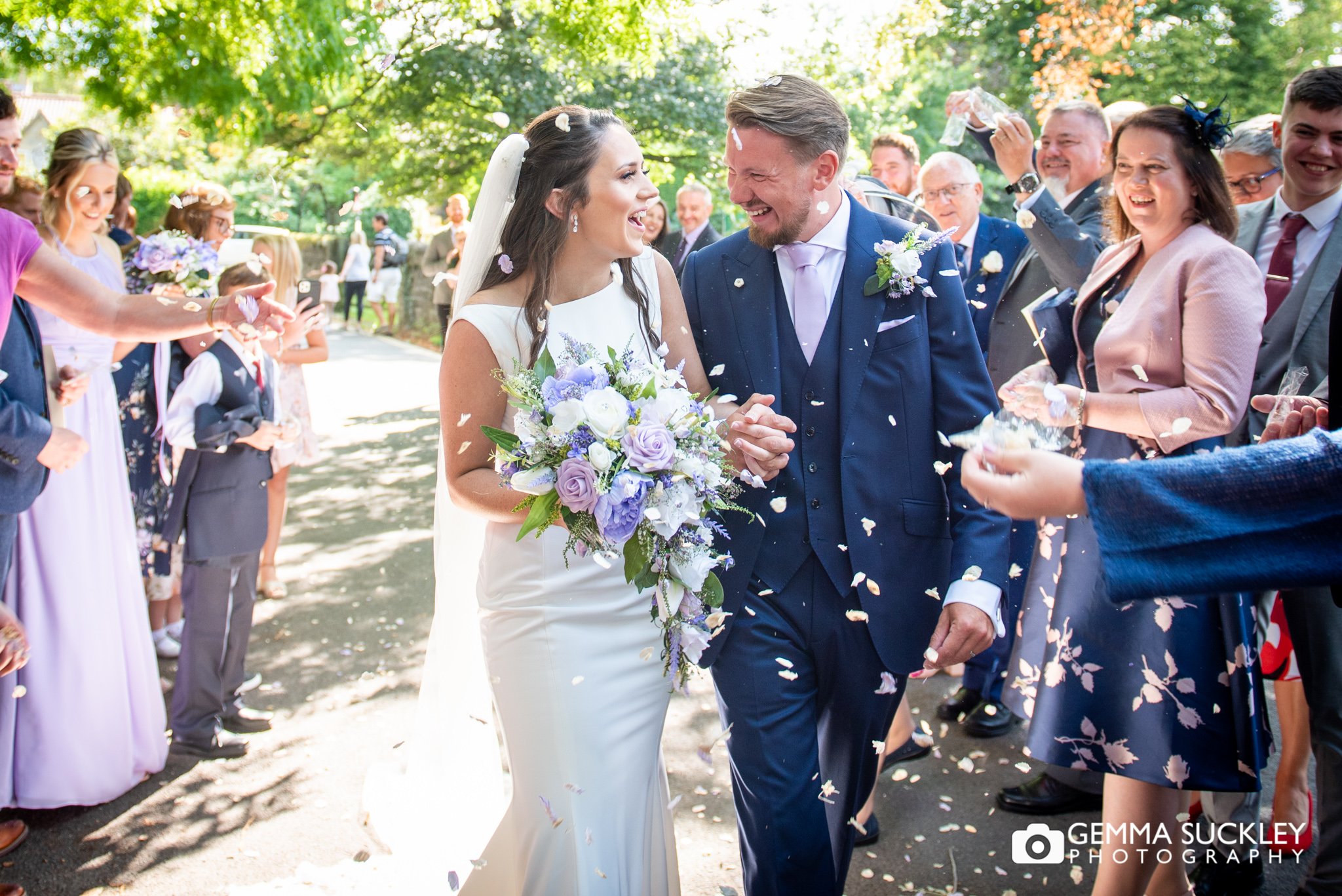 bride and groom laughing as the walk throw a confetti tunnel at wetherby church