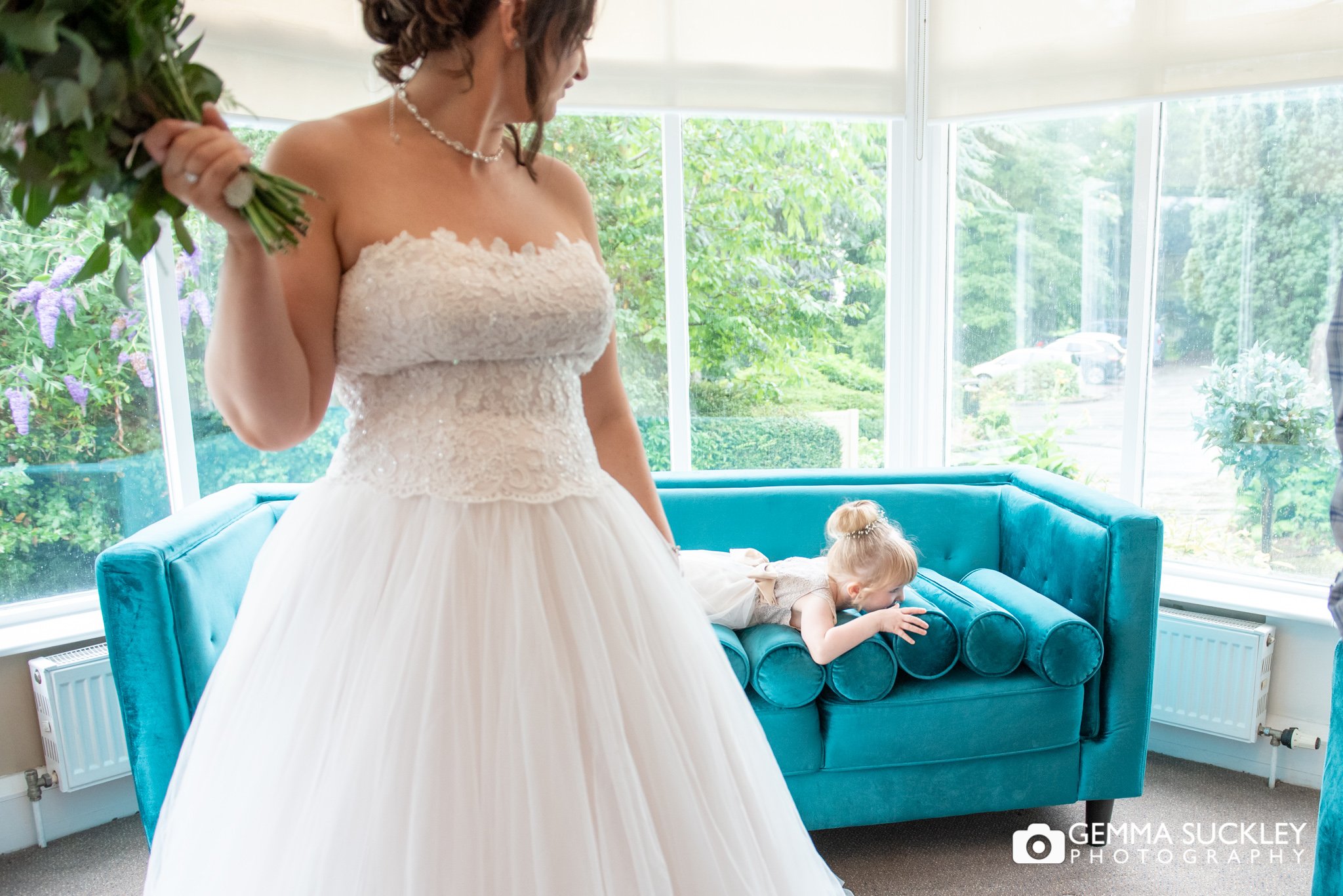 a flower girl misbehaving behind the bride whilst having her photo taken