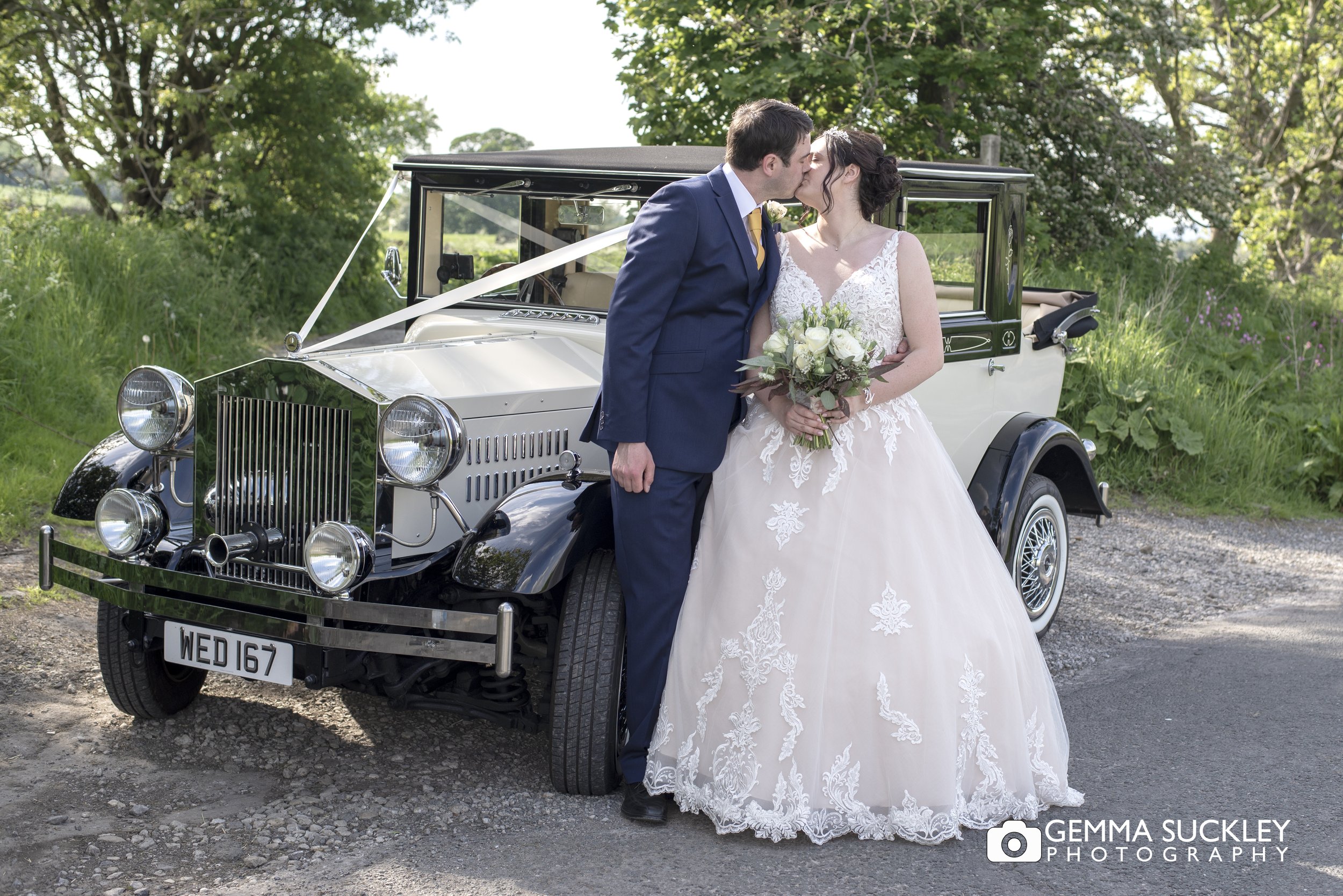 newly weds kissing by their wedding car in skipton