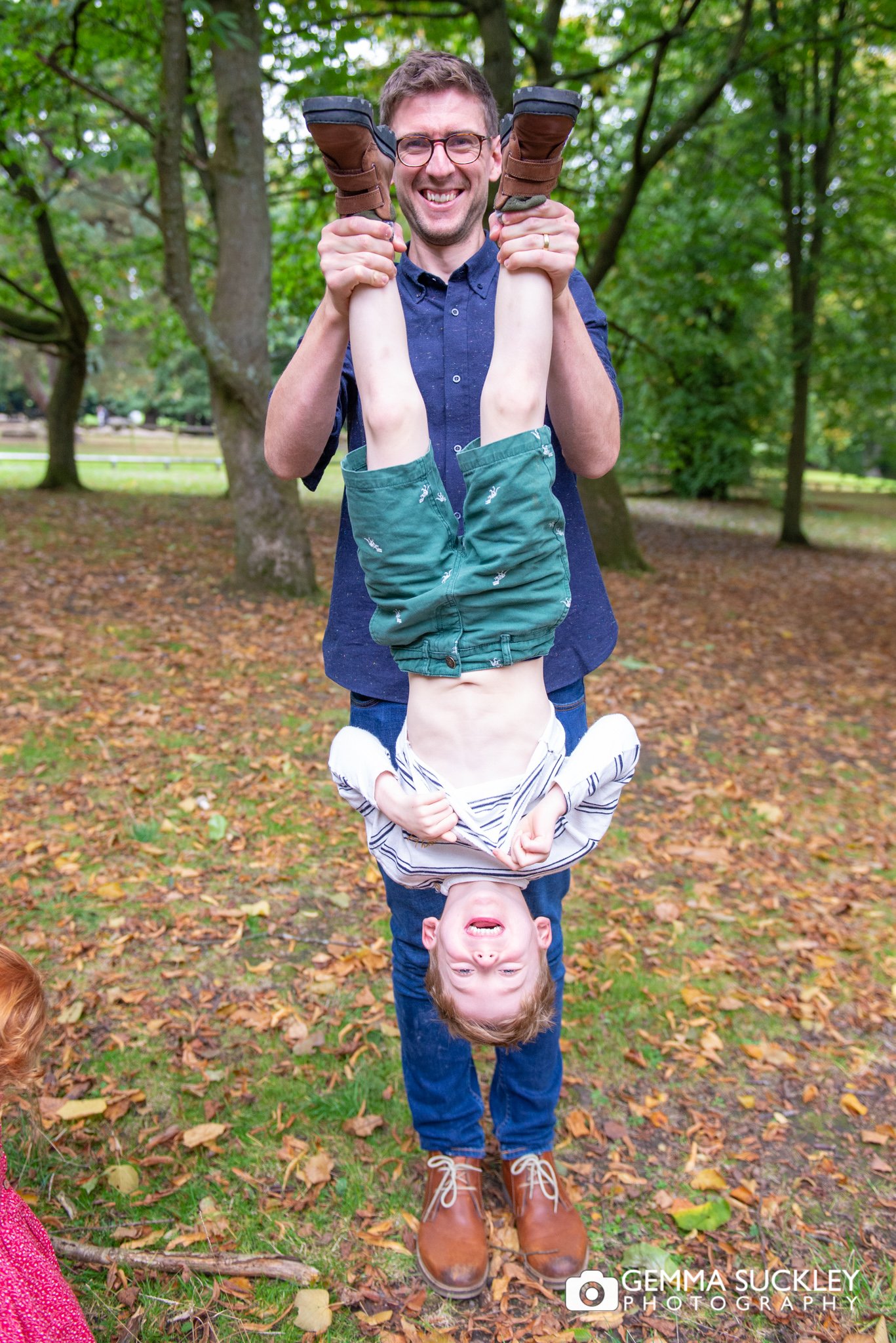 a dad holding his son upside down for a photo at st ives park in bingley