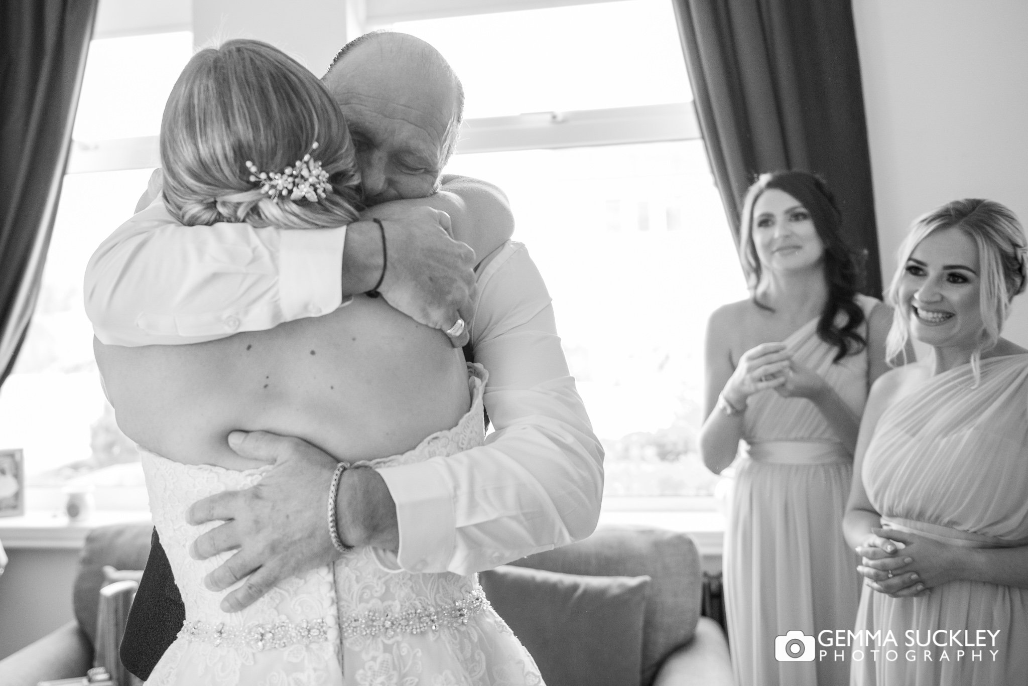 a father hugging his daughter as the bridesmaids look on in the background