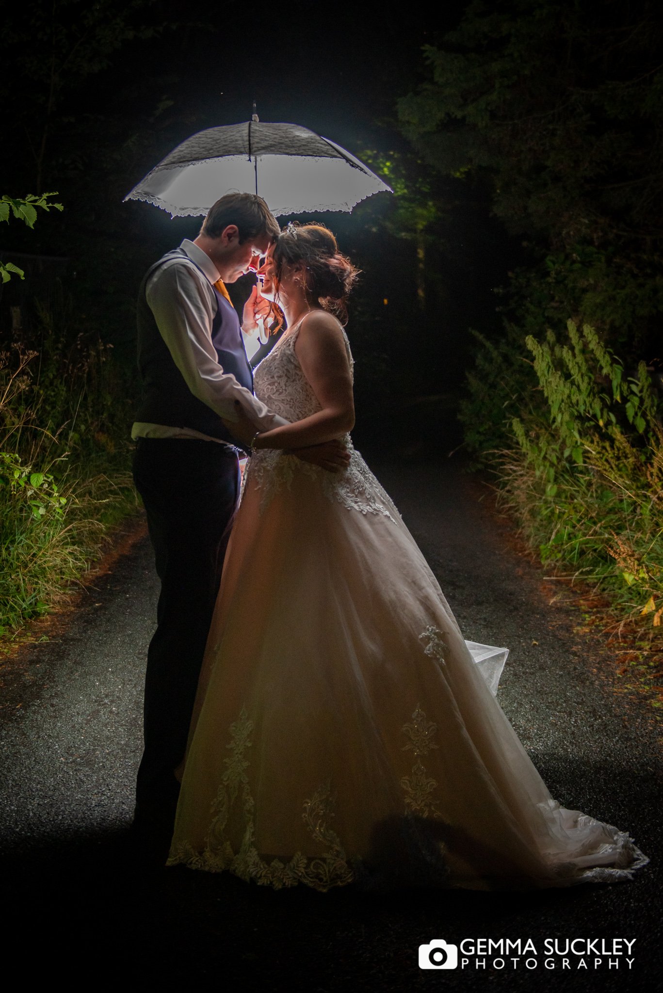 night photography of the bride and groom hugging under an umbrella