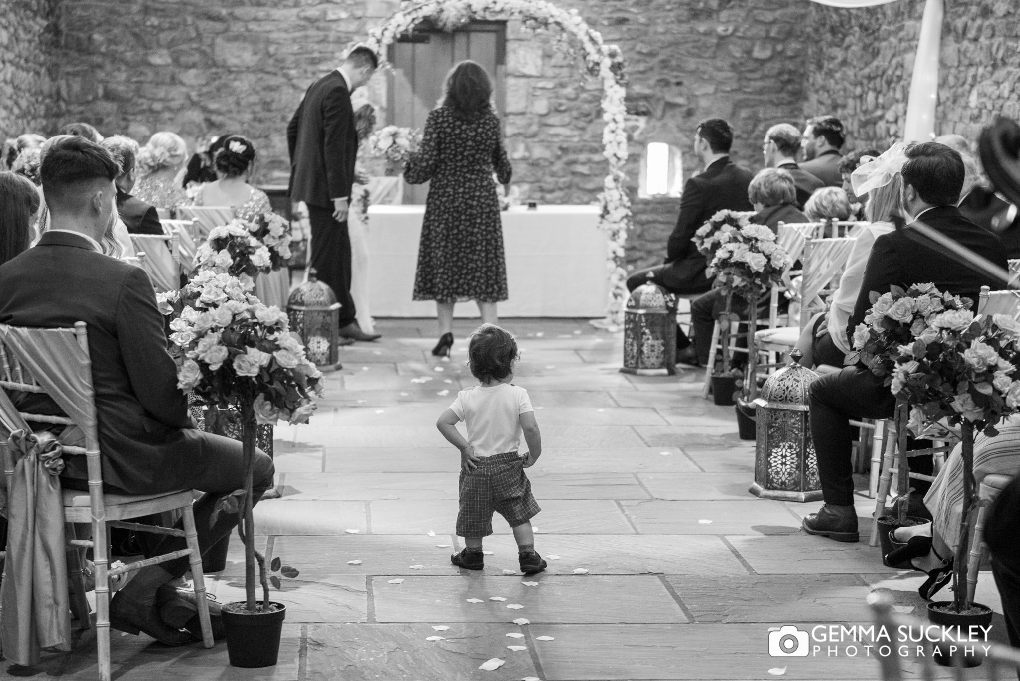 a toddler walks down the aisle at browsholme hall wedding ceremony