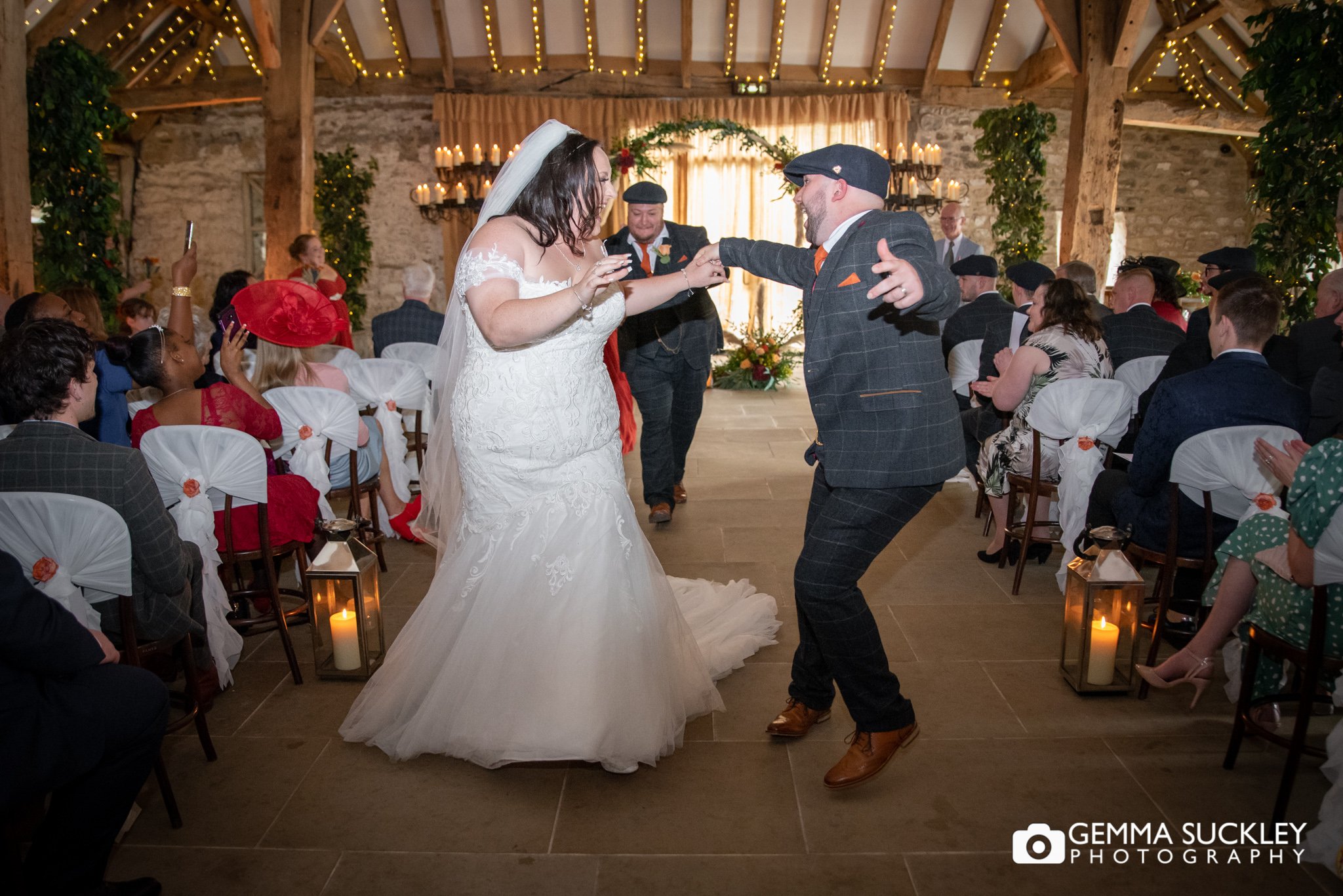 newly weds dancing up the aisle at the tithe barn