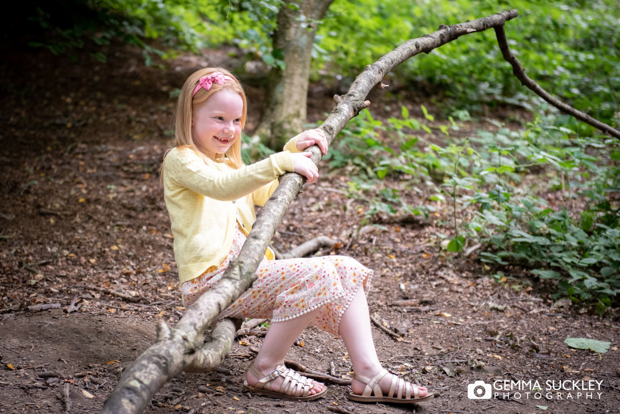 a little girl sitting in a tree branch in otley chevin forest park