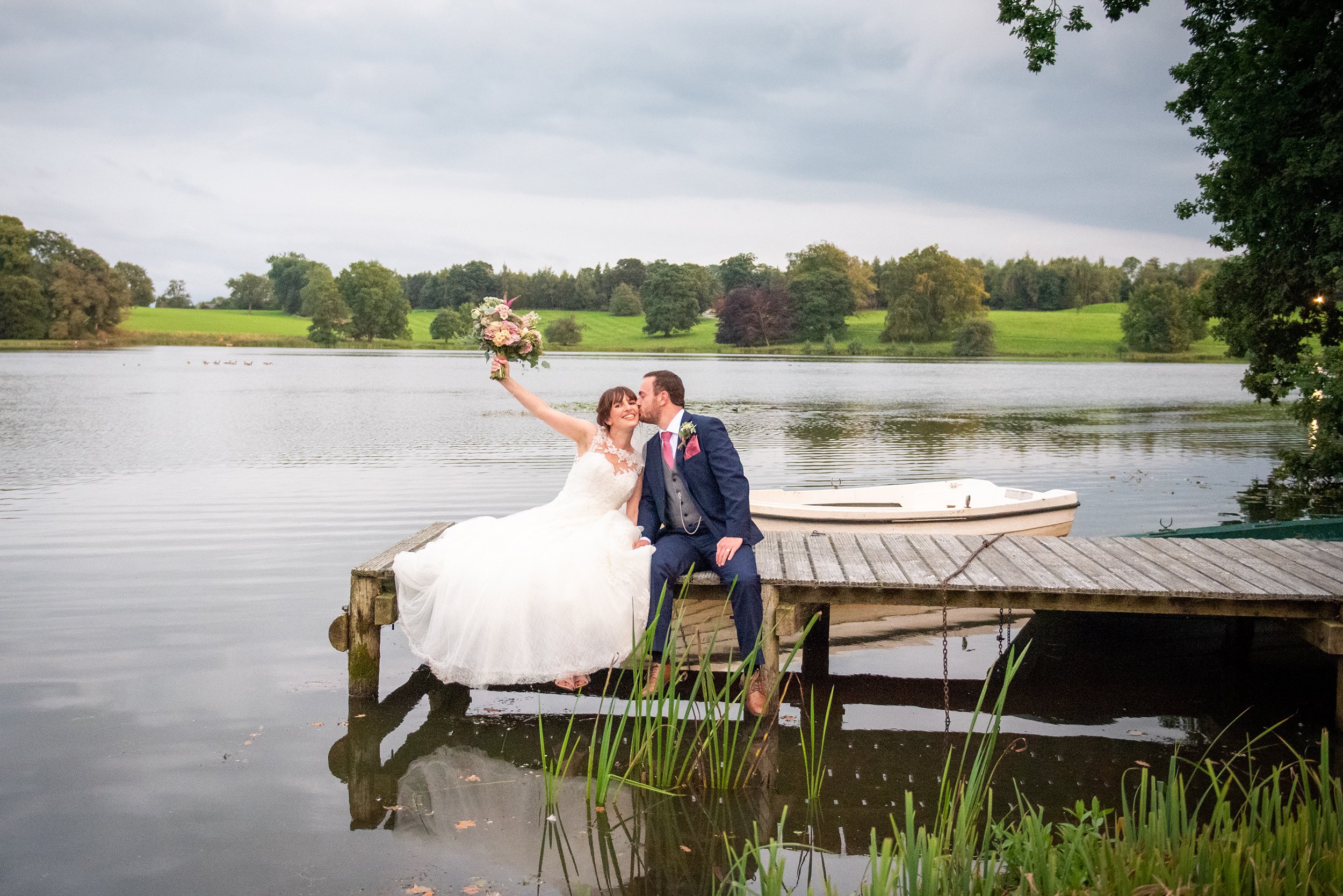 and bride and groom sat on the jetty at coniston hotel lake