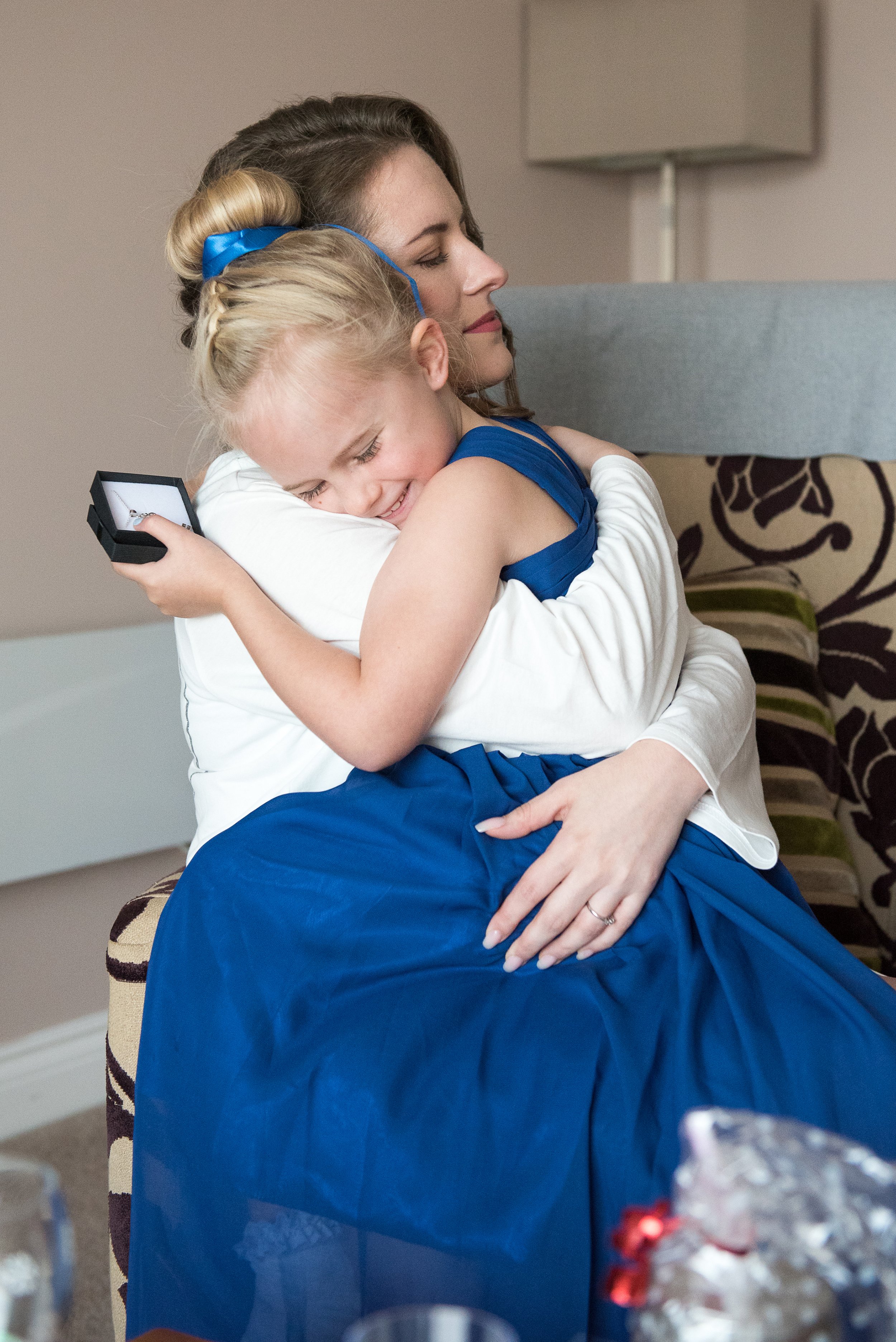 a bride cuddling the flower girl after giving her a gift