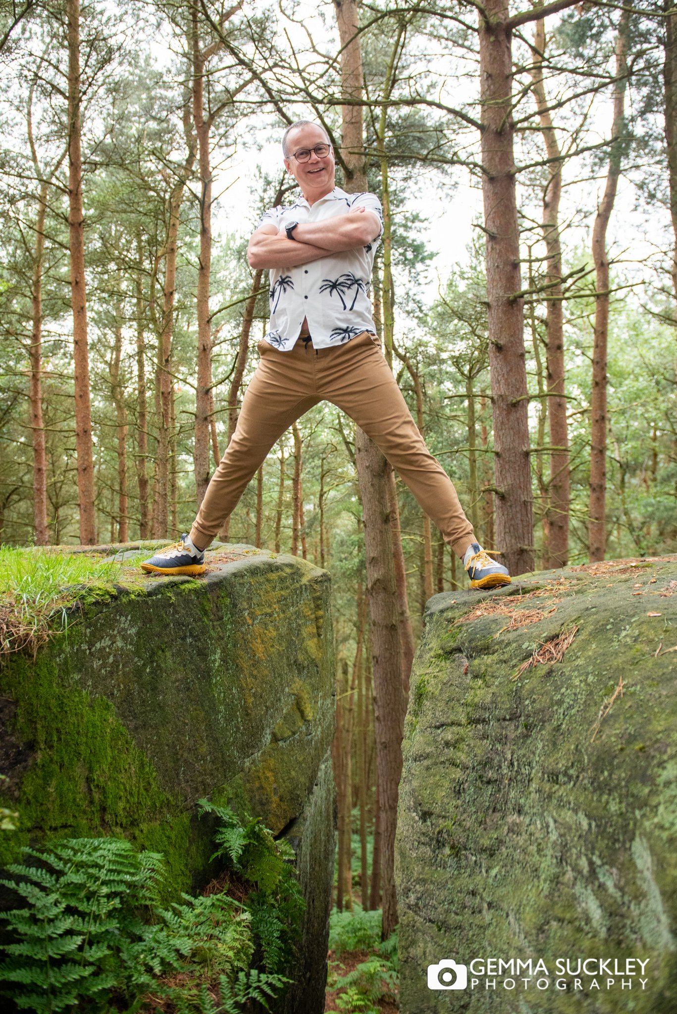 a man standing on a rock for a photo shoot in the woods