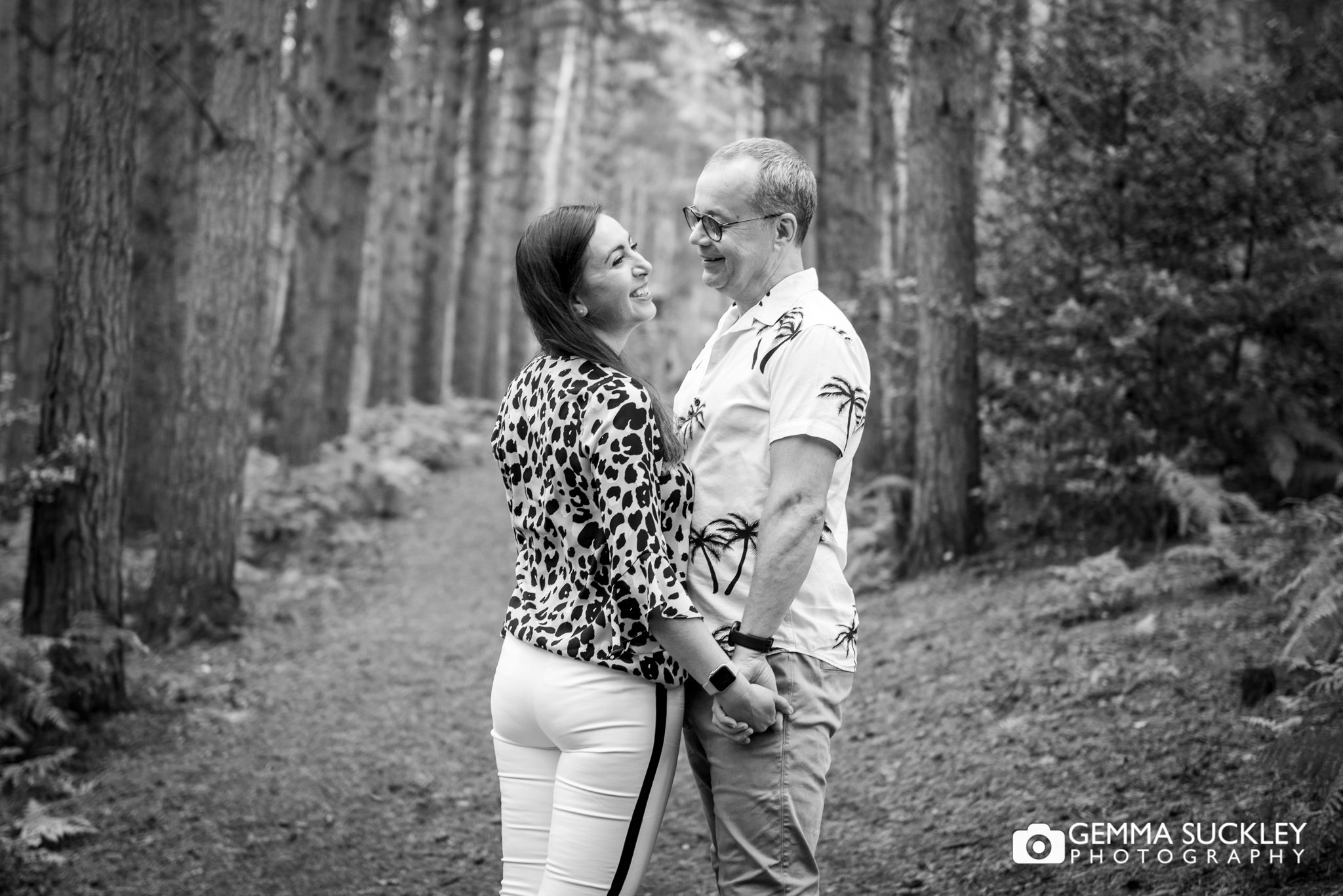 a black and white photo of a couple holding hands in cullingworth woods
