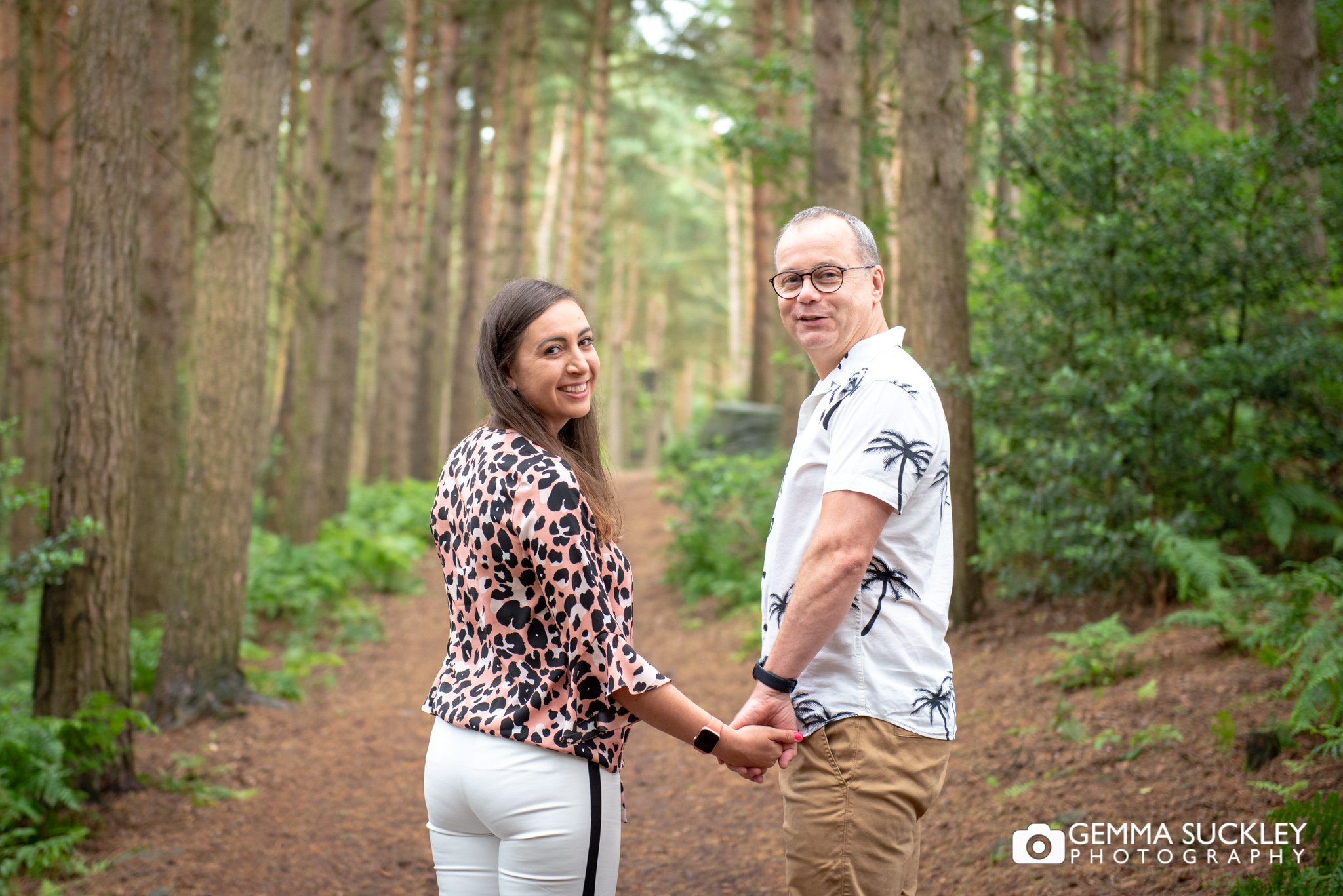 an engaged couple walking in the woods during a photo shoot