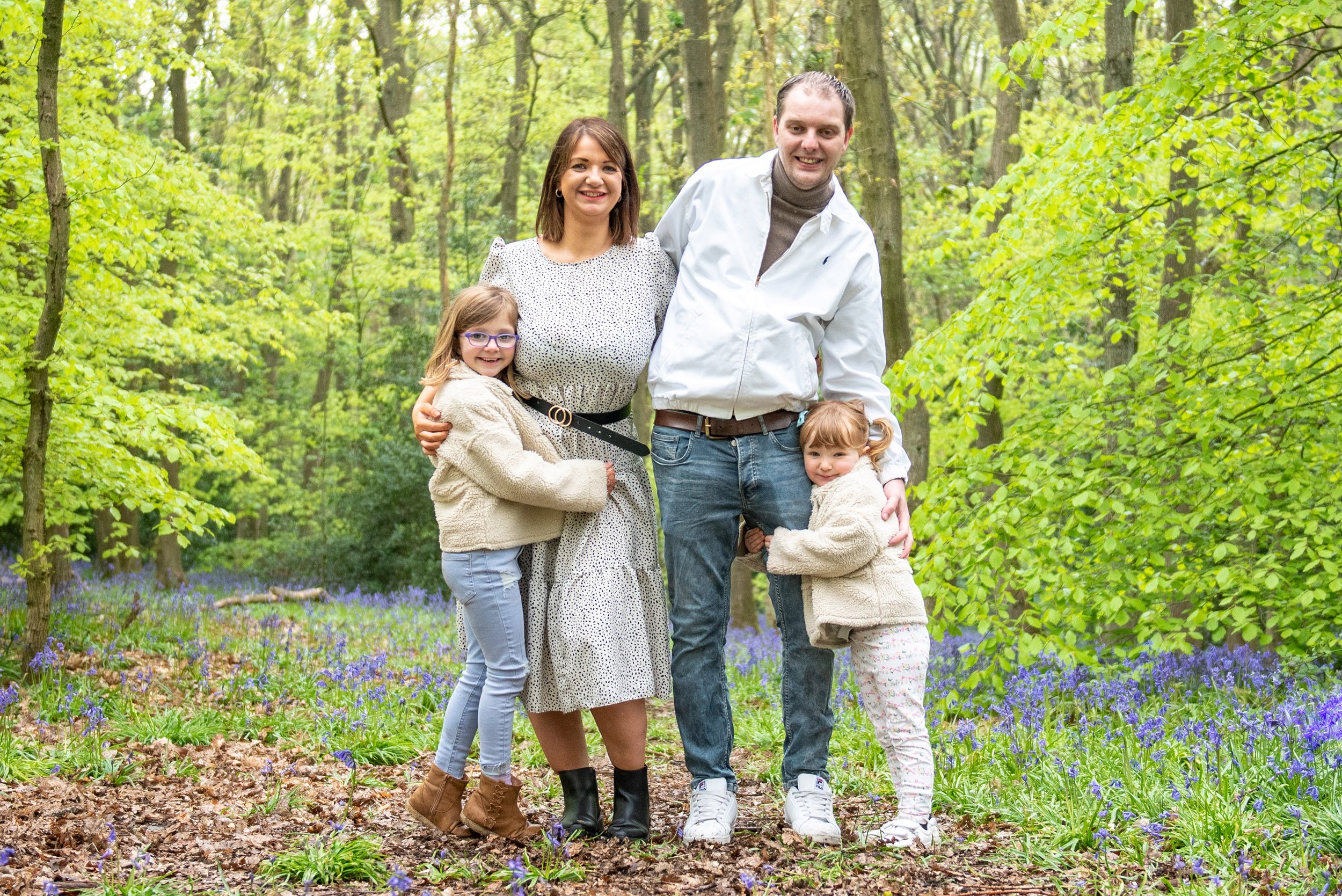 two children hugging their parent for a family photos in the bluebells