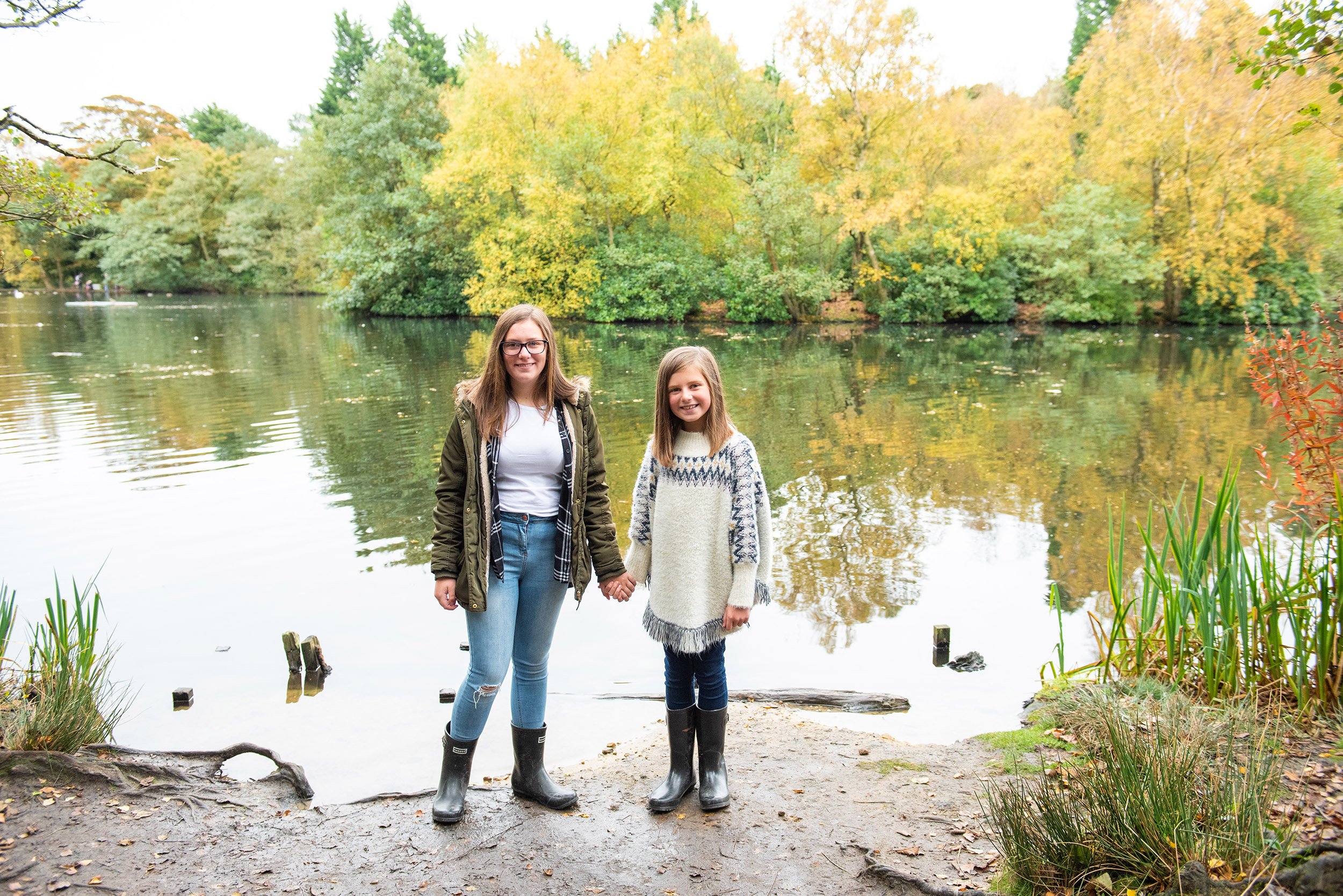 two sisters holding hands in front of the pond at st ives bingley estate 