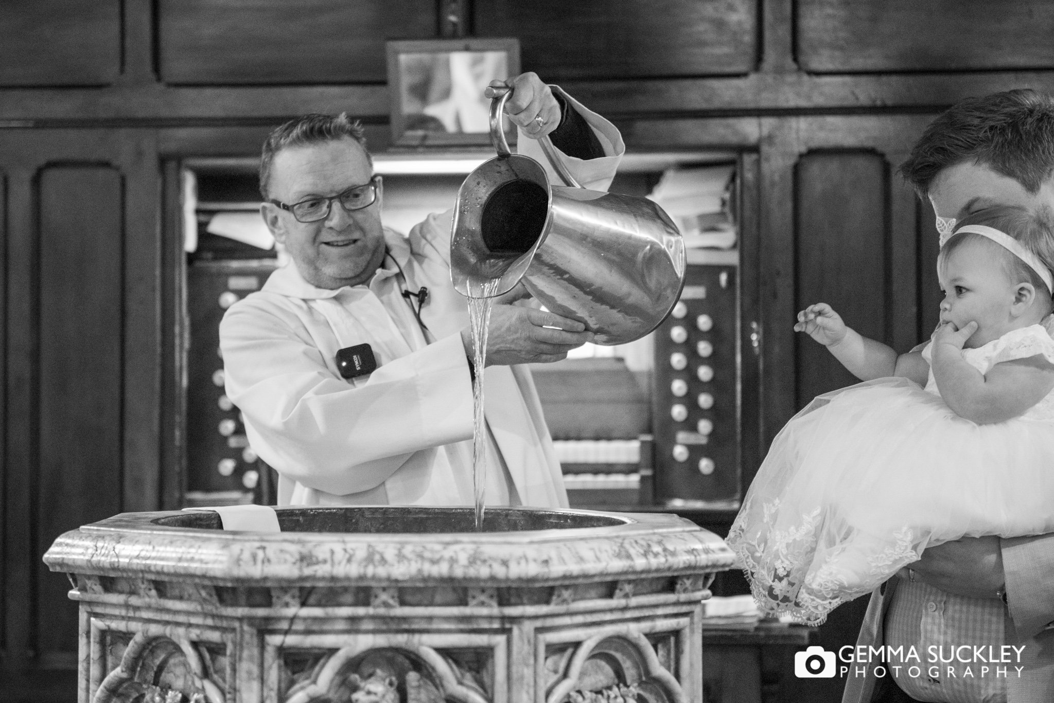a vicar pouring holy water at a christening