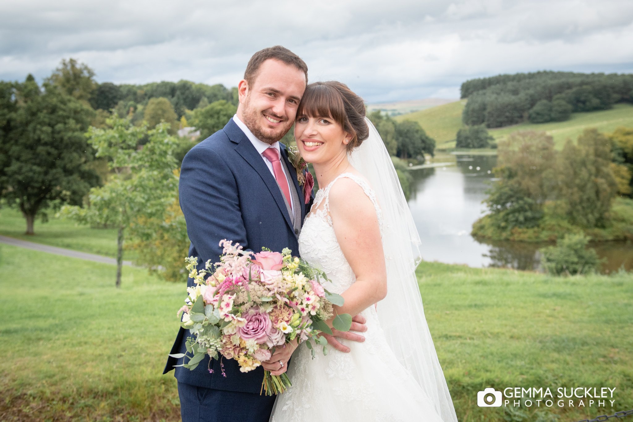 a bride and groom in front of coniston lake