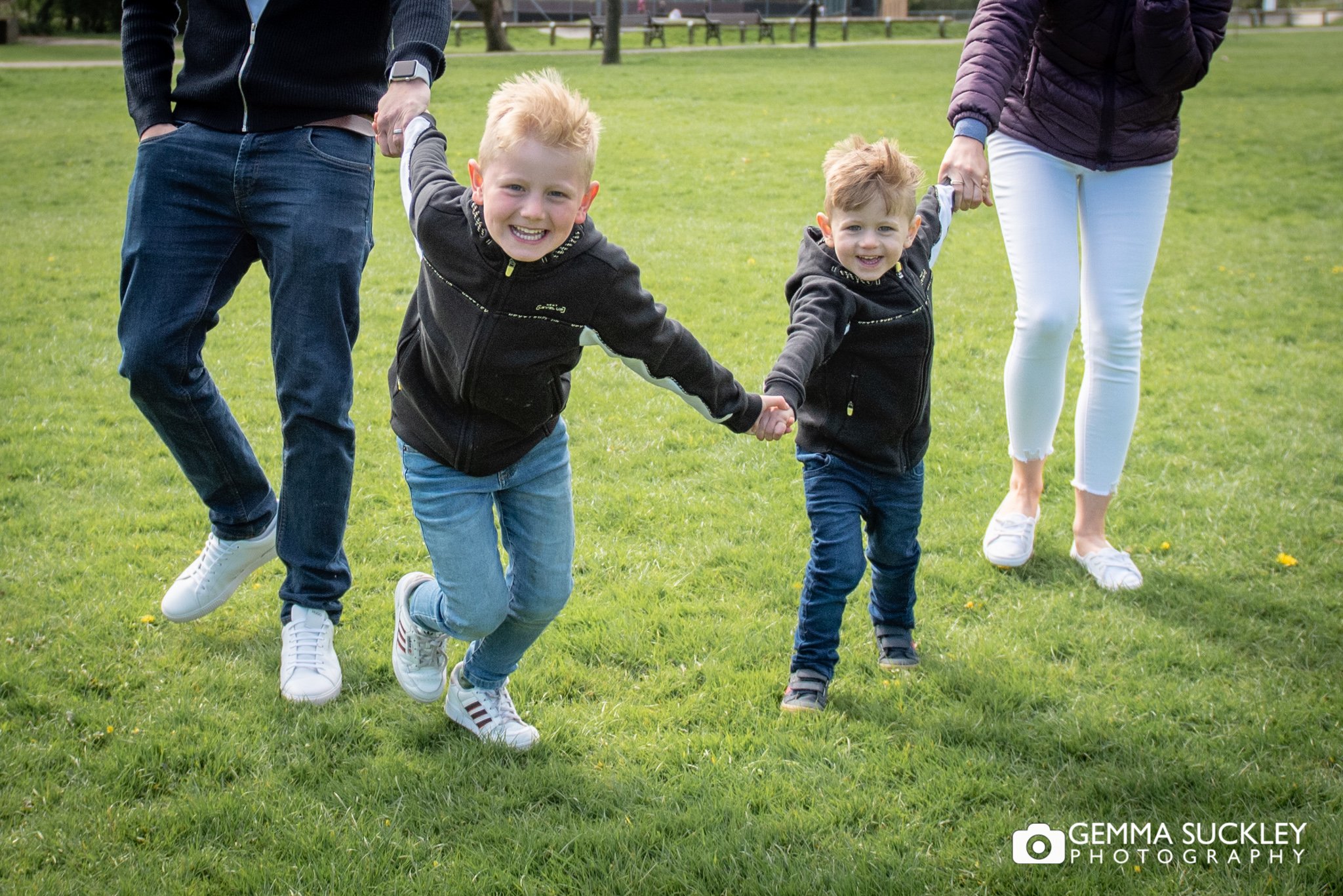 two young boys holding hands running towards the camera