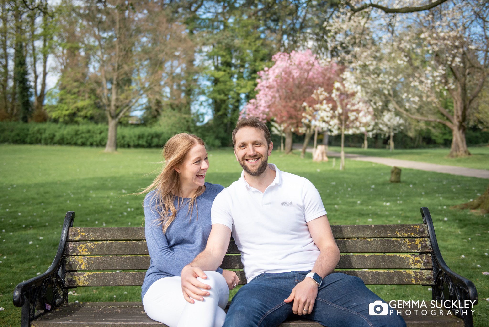 an engaged couple sitting on a bench in skipton park for their engagement photo shoot