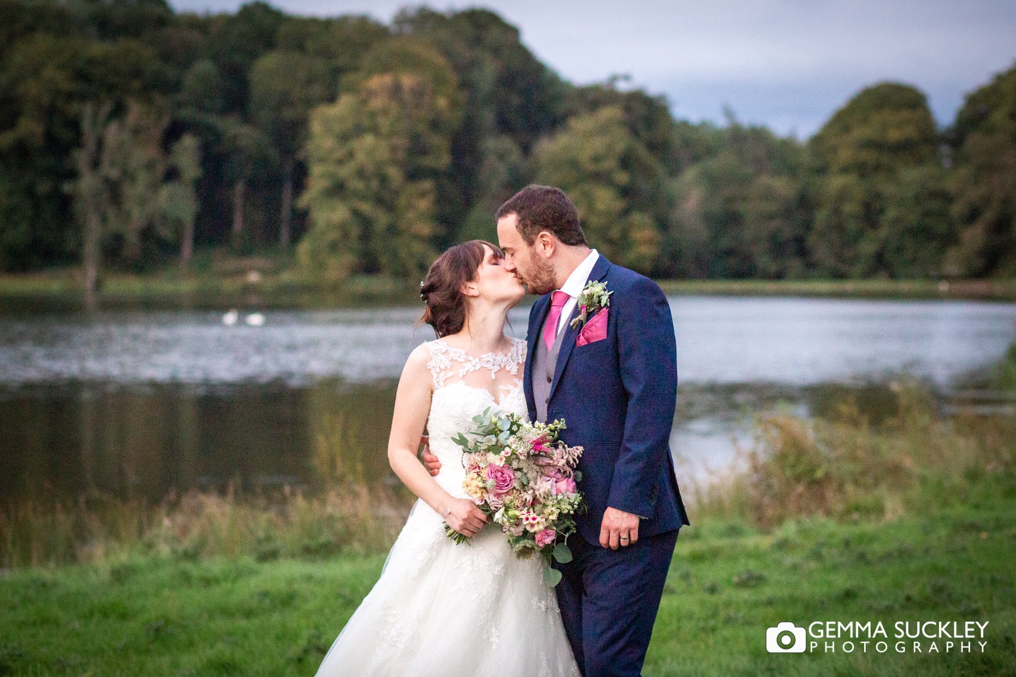 bride and groom kissing in front of the coniston lake in skipton