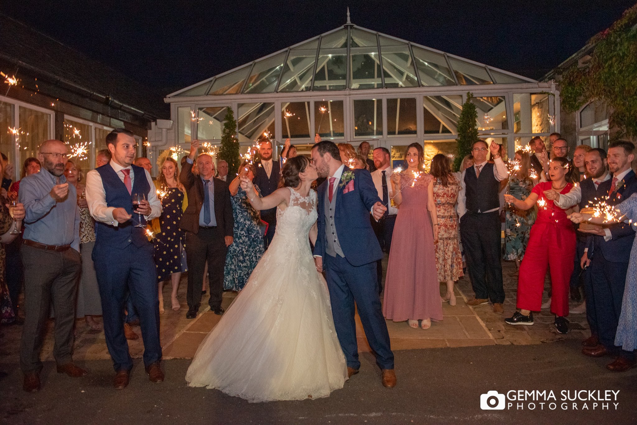 the whole wedding party waving sparklers at the coniston hotel in skipton 