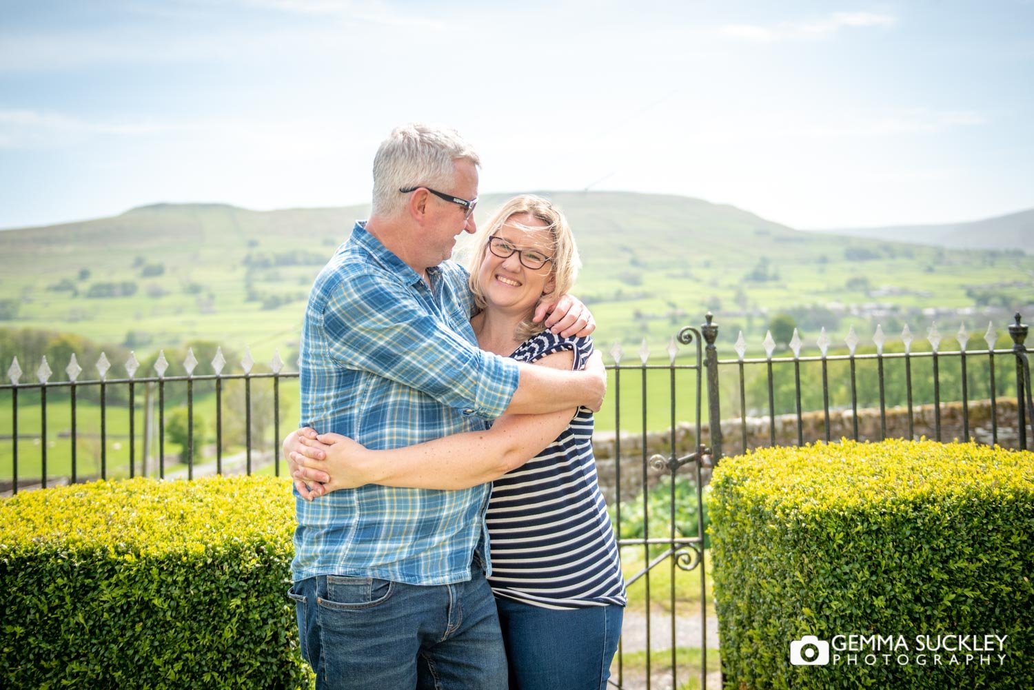 a couple hugging with the yorkshire dales scenery behind 