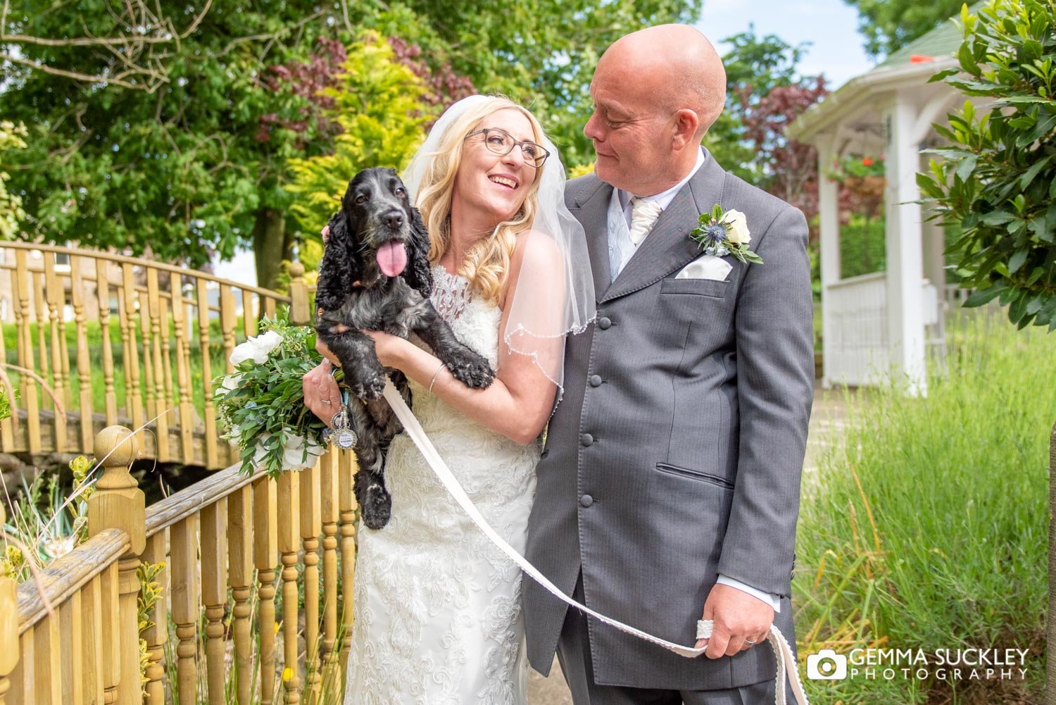 a bride and groom holding their dog outside steeton hall