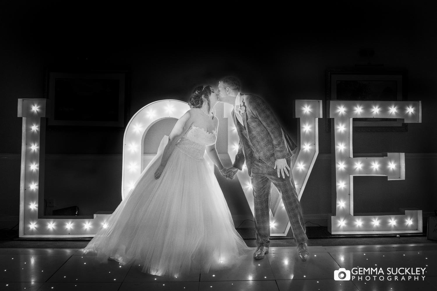 bride and groom kissing in front of love letters at hollins hall