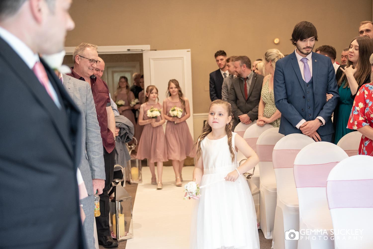 the flower girl walking down the aisle at hollins hall