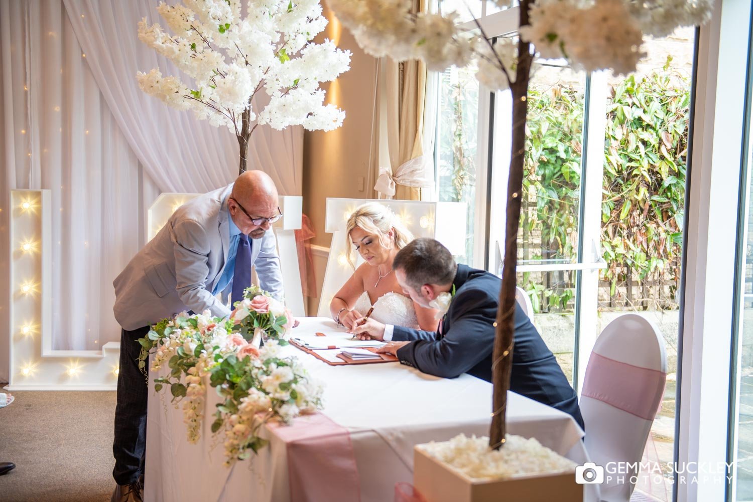 the bride and groom signing the registrar at hollins hall wedding