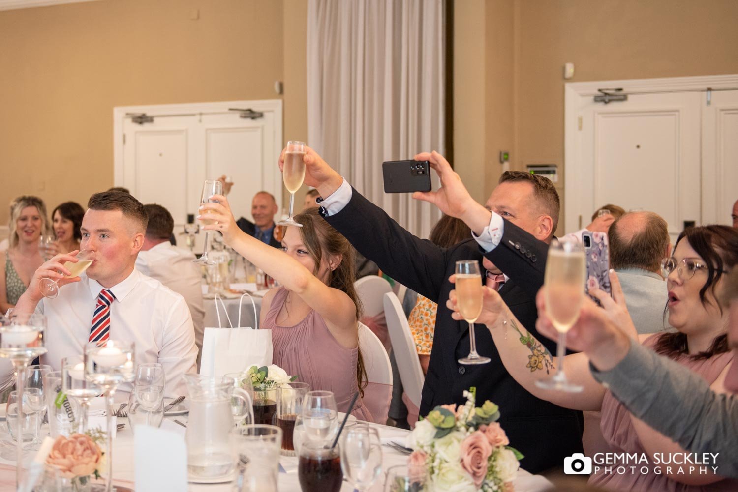 wedding guests raising their glasses at hollins hall wedding speeches