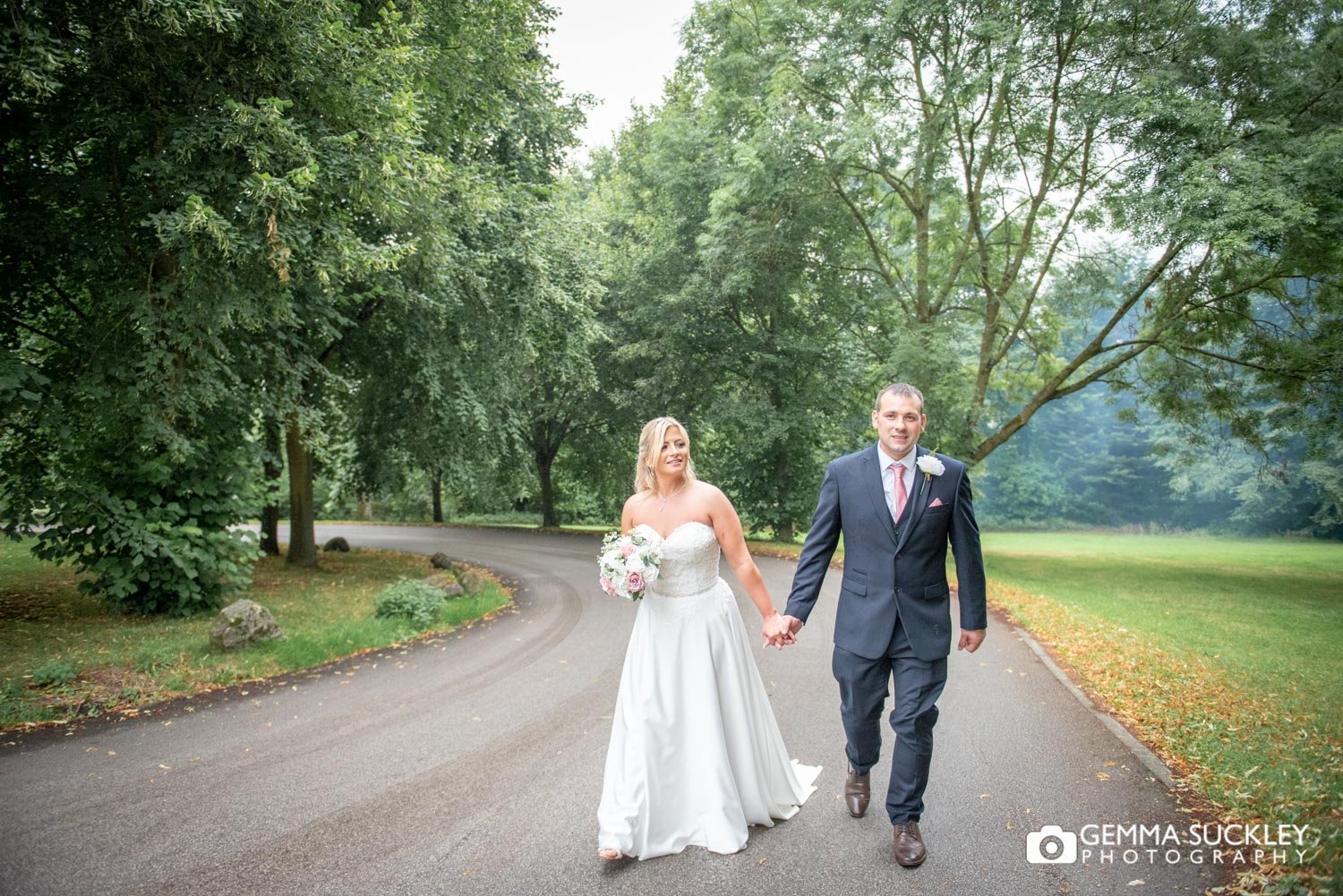 the bride and groom walk up the drive at hollins hall country hotel