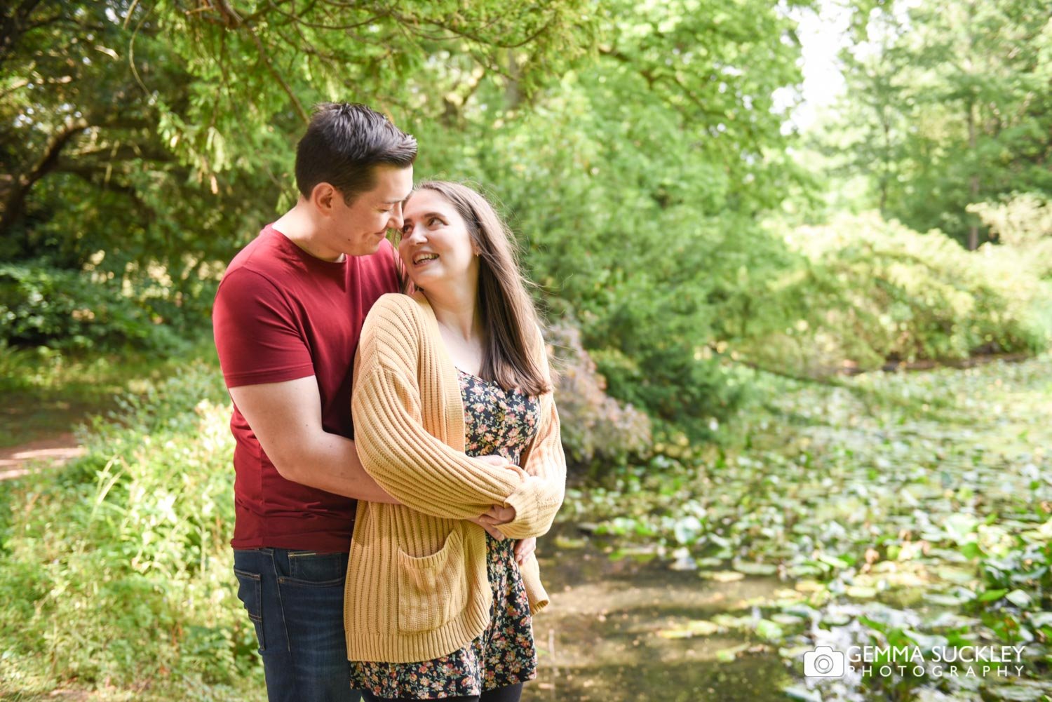 an engaged couple by the lake at swinton park estate in masham