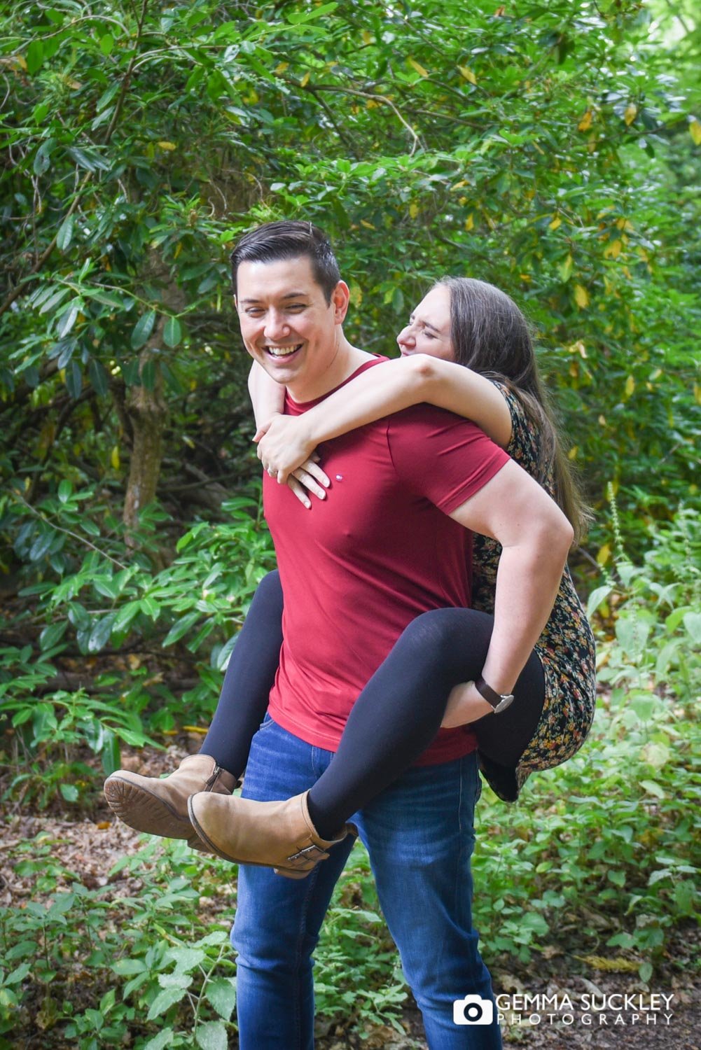 a couple laughing as he gives her a piggyback
