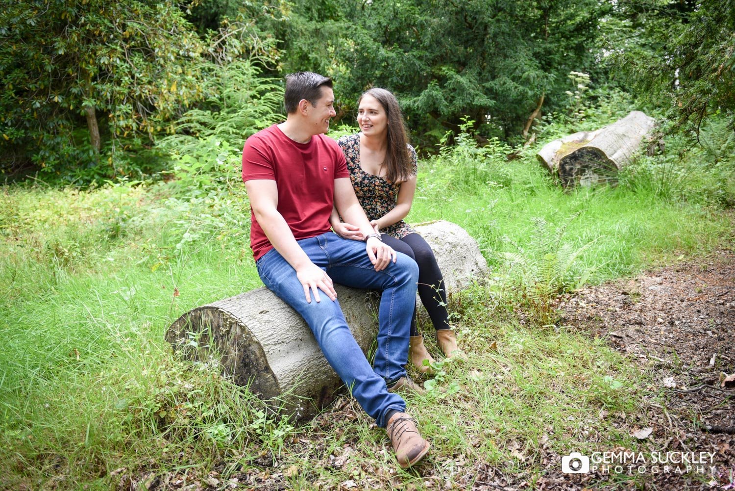 engaged couple sitting on a log in swinton park woods