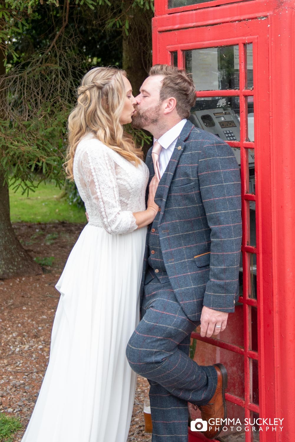 bride and groom kiss  next to a red phone box