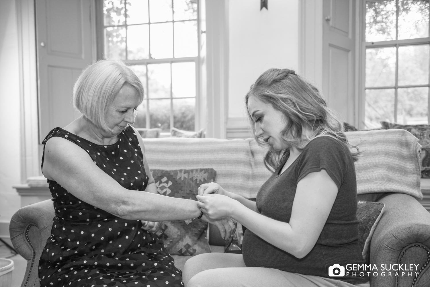 a bridesmaid putting a bracelet on the brides mum