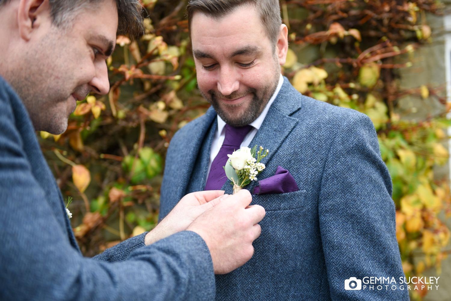 the best man putting on the groom's buttonhole