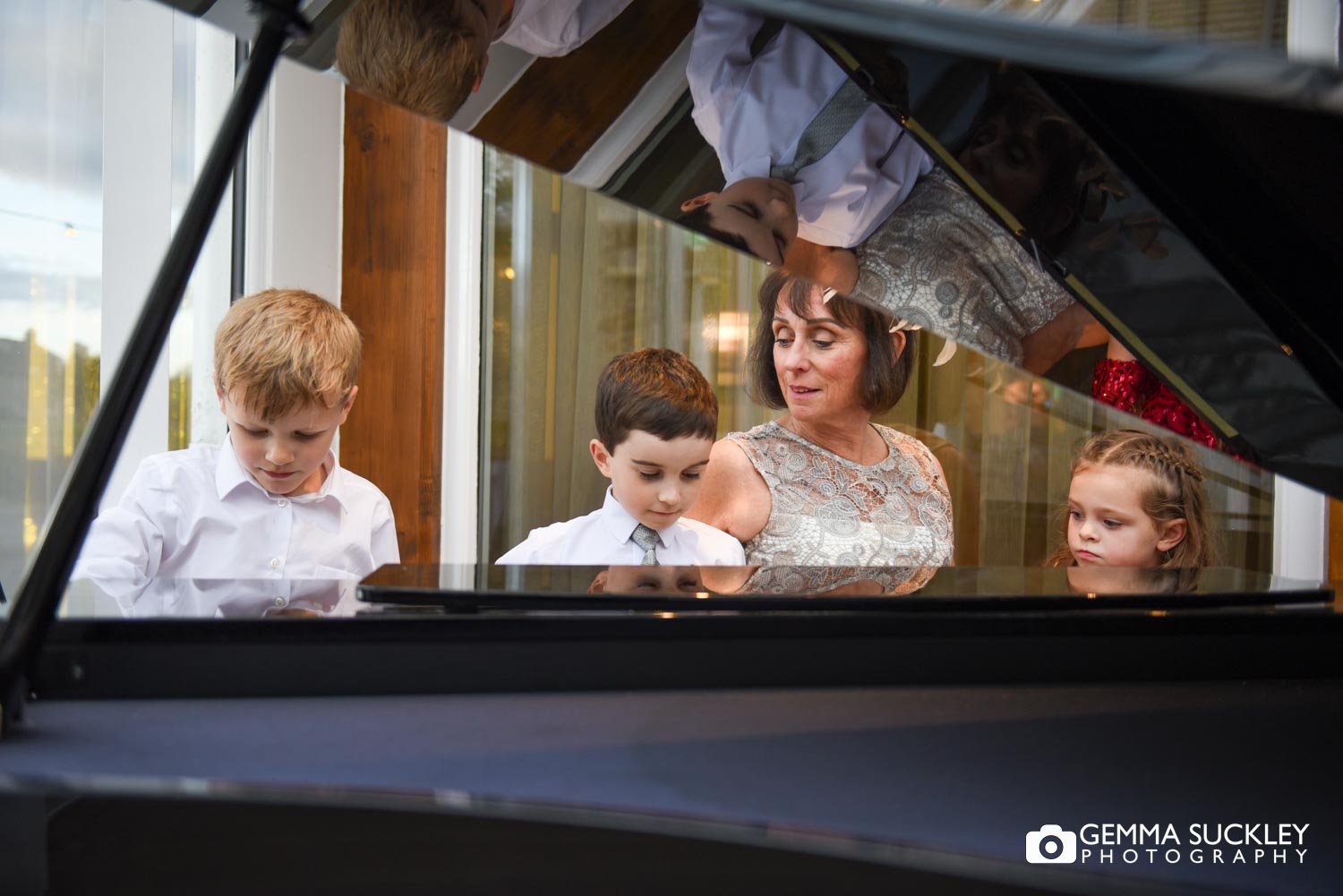 a lady sat at the piano with children in the conservatory at coniston hotel 