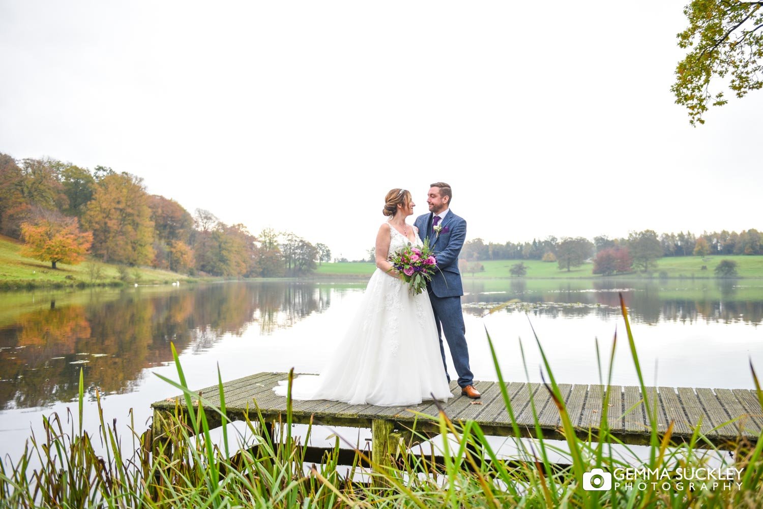 the bride and groom on the jetty at coniston hotel lake in the autumn