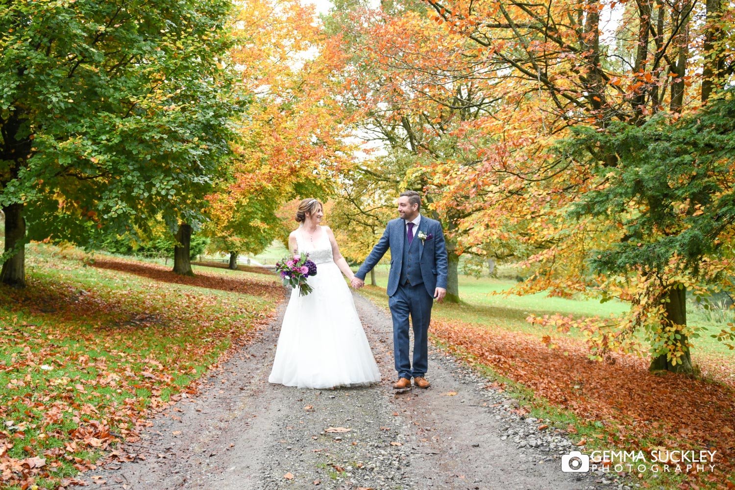 just married couple walk on conston hotel estate surrounded by autumn leaves