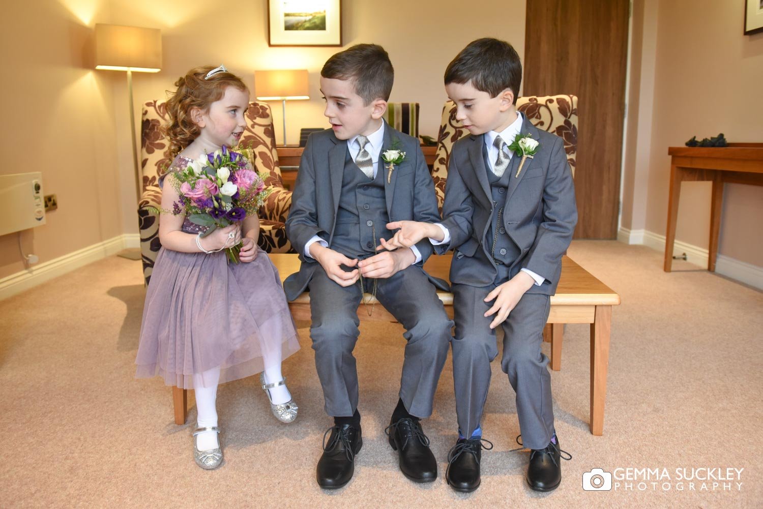 two young pageboys talk to the flower girl