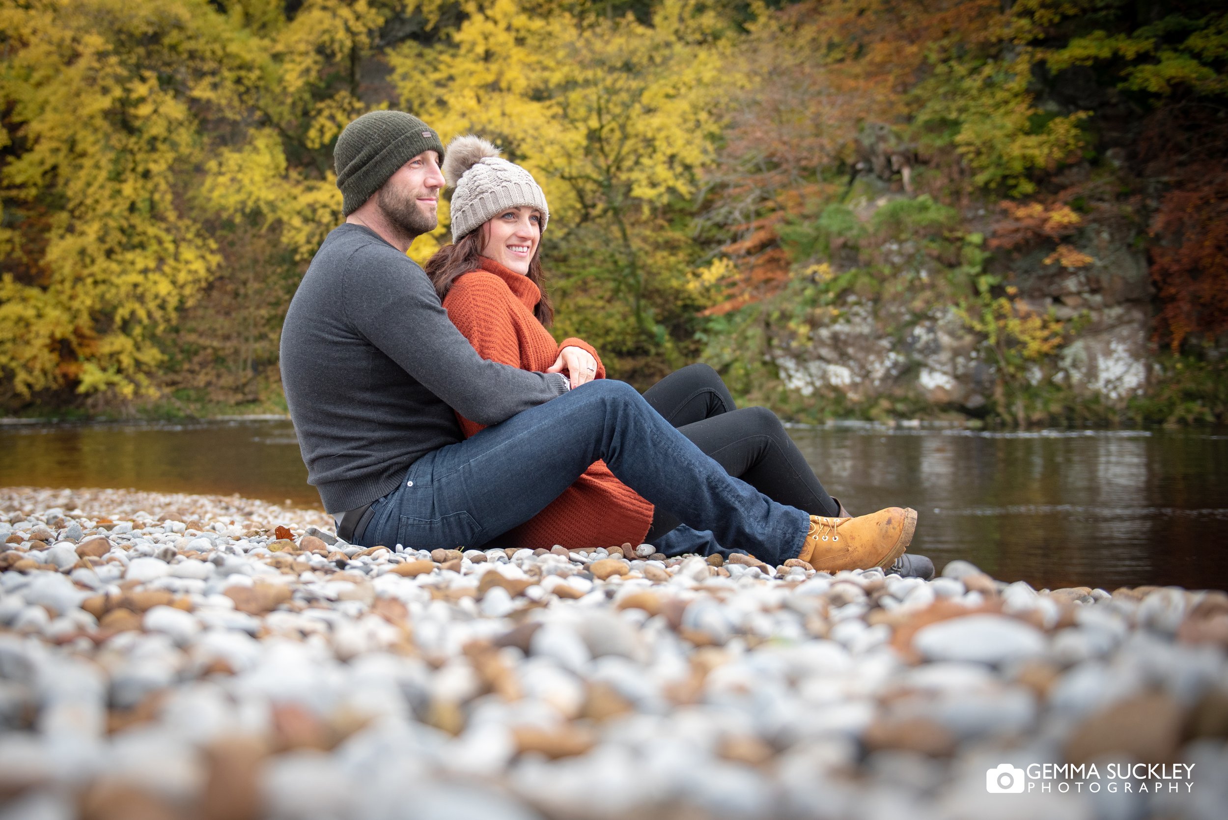 Engaged couple sitting at the river at bolton abbey estate