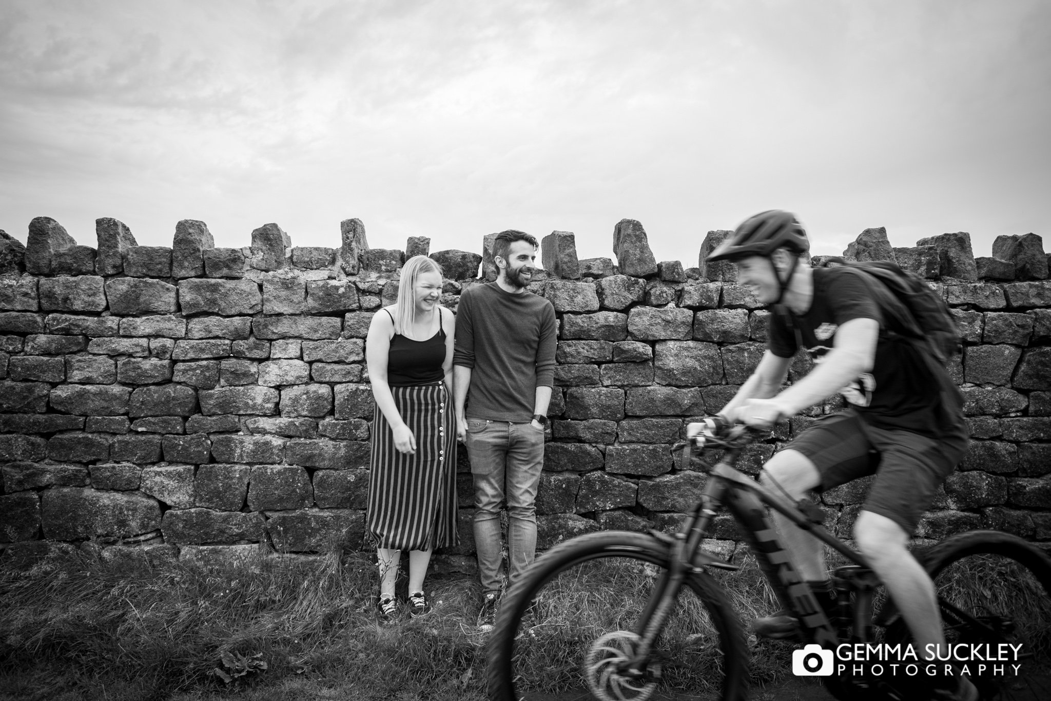 engaged couple abot to have their photo taken as a cyclist passes on cowling pinnacle