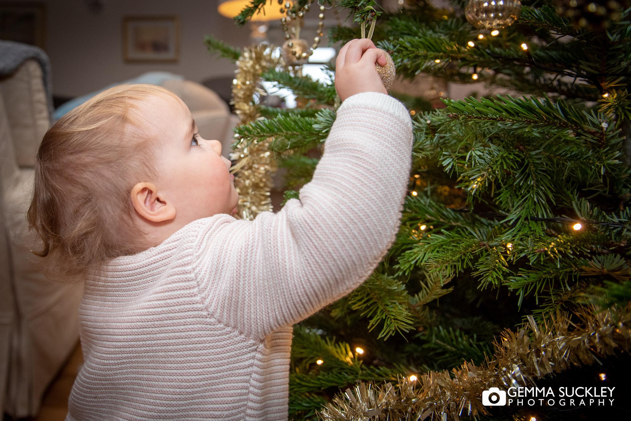 a little girl putting a bauble on a Christmas tree