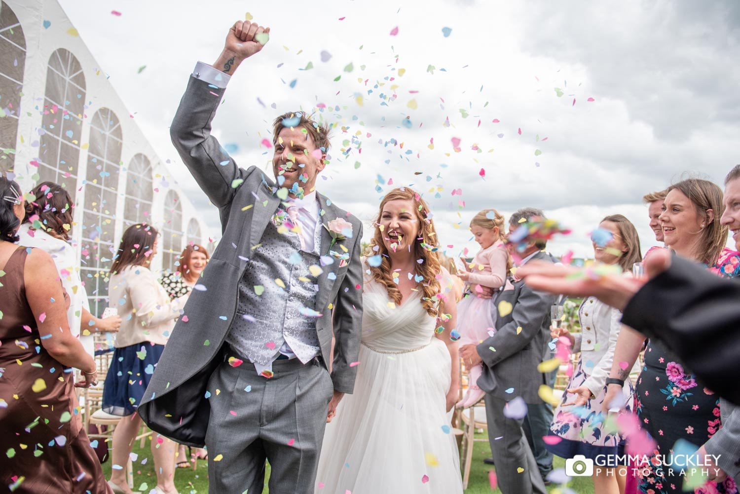 bride and groom laughing at confetti is thrown at them